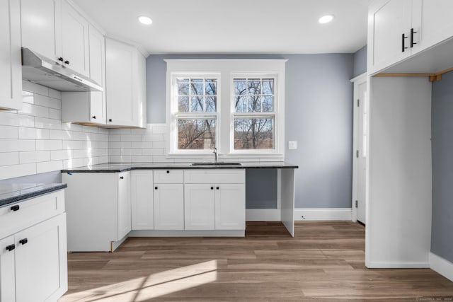 kitchen featuring backsplash, white cabinetry, light wood-type flooring, and sink