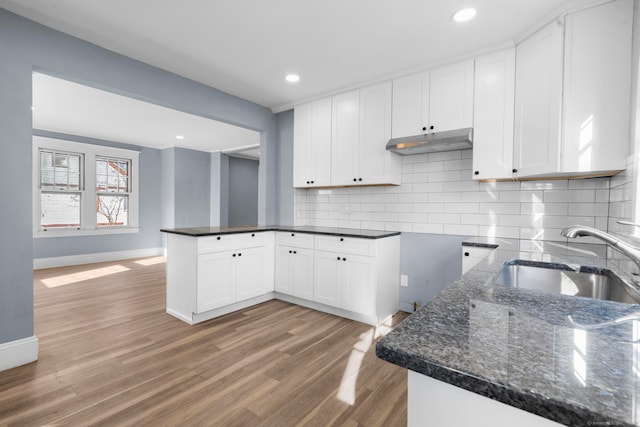 kitchen featuring kitchen peninsula, white cabinetry, light hardwood / wood-style flooring, and sink