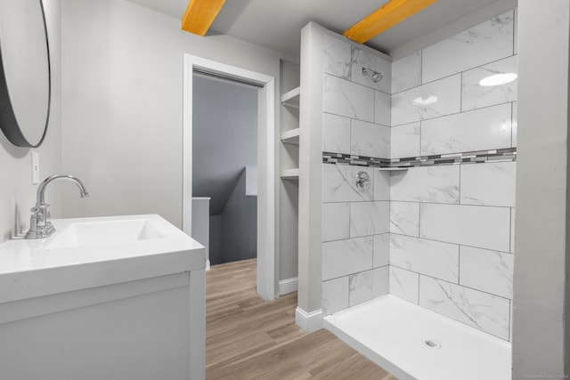 bathroom with tiled shower, vanity, and hardwood / wood-style flooring