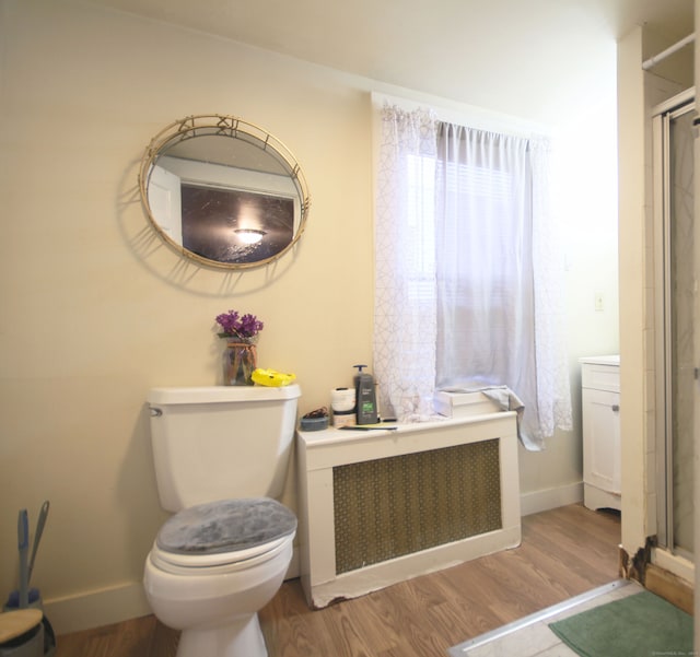 bathroom featuring walk in shower, radiator, wood-type flooring, and toilet