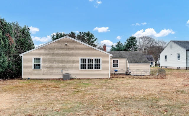 rear view of house with central AC unit and a lawn