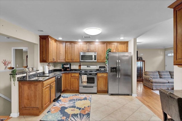 kitchen featuring sink, stainless steel appliances, light hardwood / wood-style flooring, kitchen peninsula, and dark stone counters