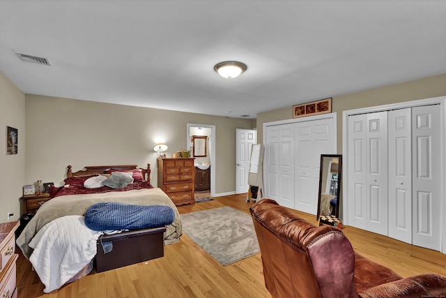 bedroom featuring hardwood / wood-style floors, connected bathroom, and two closets