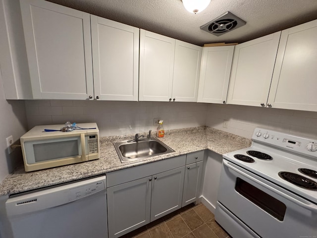 kitchen featuring sink, dark tile patterned floors, white appliances, decorative backsplash, and white cabinets