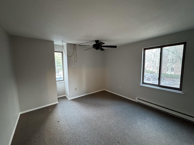 empty room featuring dark colored carpet, ceiling fan, and a baseboard heating unit