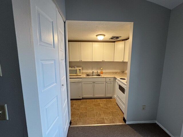 kitchen featuring white appliances, white cabinets, tile patterned floors, sink, and a textured ceiling