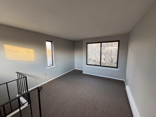 carpeted empty room with a textured ceiling