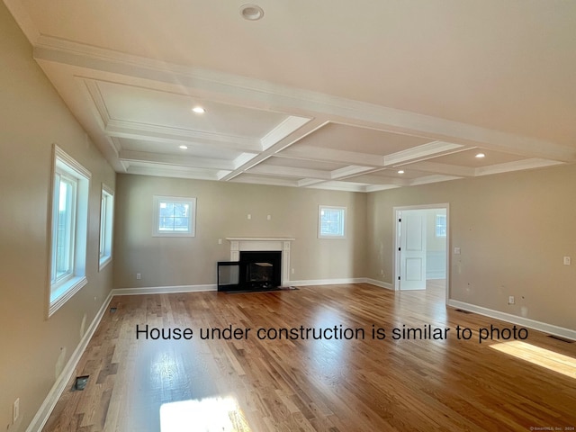 unfurnished living room featuring plenty of natural light, beam ceiling, wood-type flooring, and coffered ceiling