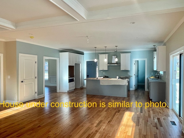 kitchen featuring white cabinetry, a center island, wall chimney exhaust hood, dark hardwood / wood-style floors, and decorative light fixtures