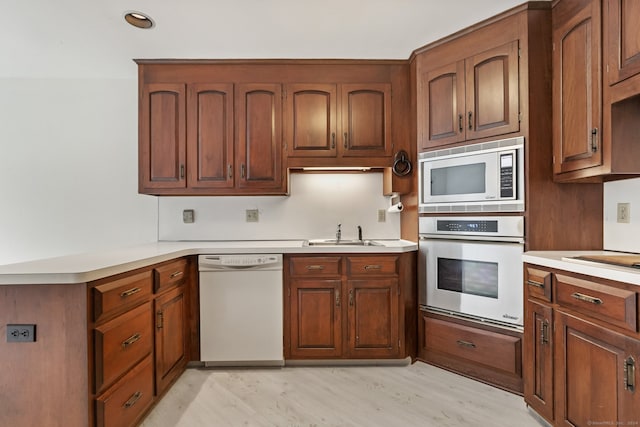 kitchen with appliances with stainless steel finishes, light hardwood / wood-style flooring, and sink