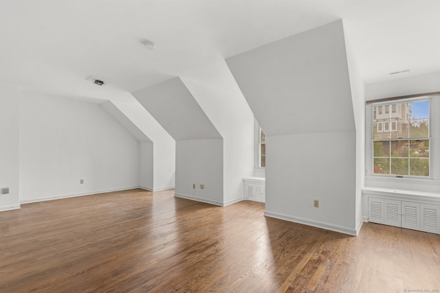 additional living space with hardwood / wood-style floors and lofted ceiling