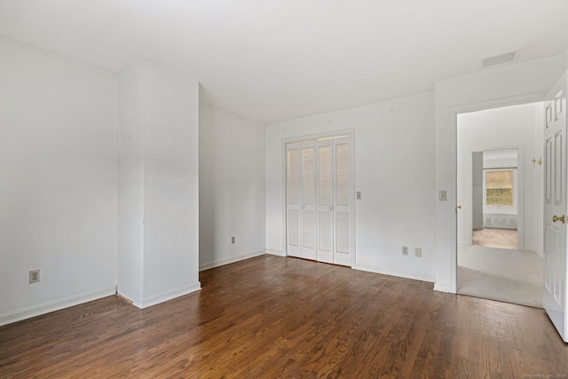 unfurnished bedroom with dark hardwood / wood-style flooring and a closet