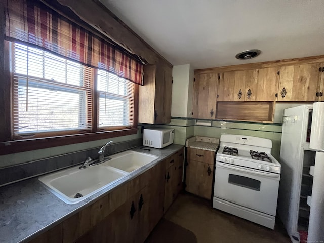 kitchen with a wealth of natural light, fridge, white range with gas cooktop, and sink