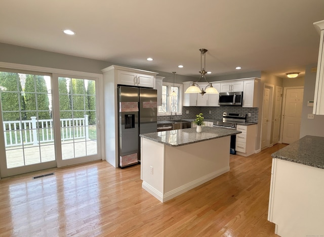 kitchen featuring white cabinets, pendant lighting, stainless steel appliances, and plenty of natural light