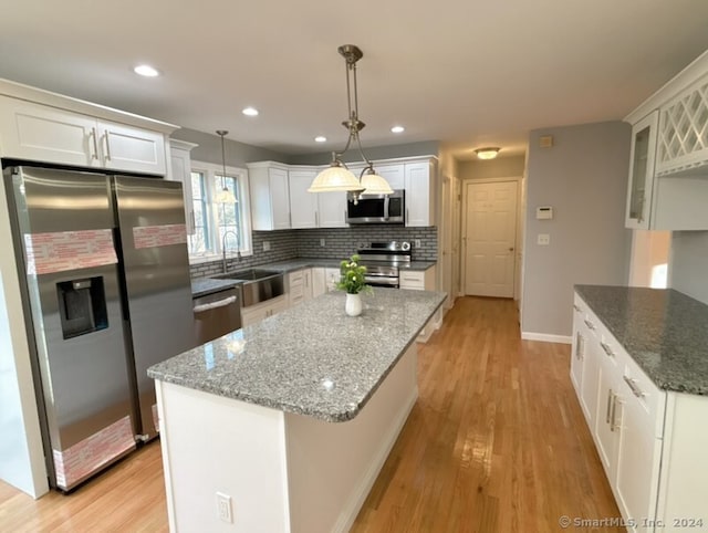 kitchen with stainless steel appliances, sink, pendant lighting, white cabinets, and a center island