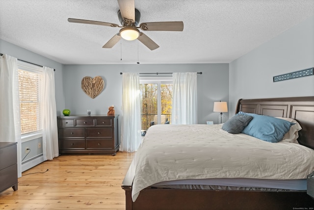 bedroom with a textured ceiling, a baseboard radiator, light hardwood / wood-style flooring, and ceiling fan