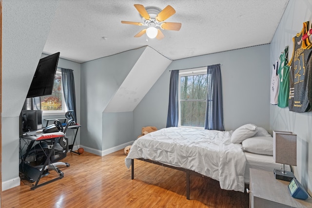 bedroom with multiple windows, ceiling fan, light hardwood / wood-style flooring, and a textured ceiling