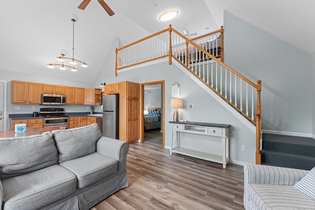 living room with hardwood / wood-style floors, high vaulted ceiling, and ceiling fan with notable chandelier