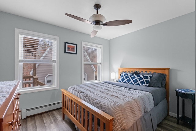 bedroom featuring hardwood / wood-style floors, ceiling fan, baseboard heating, and multiple windows