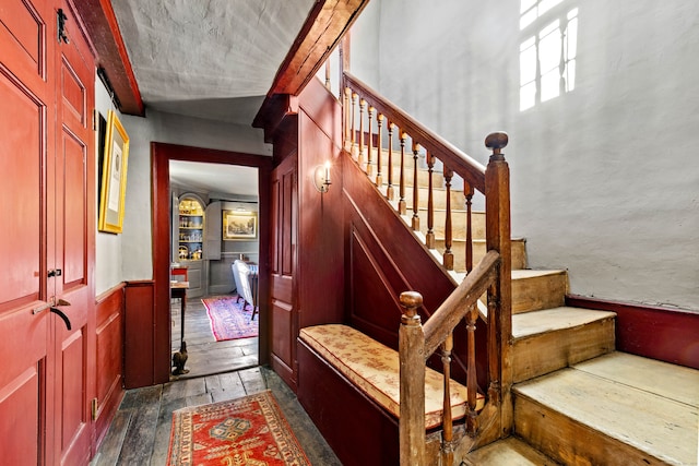 stairs with wood-type flooring and crown molding