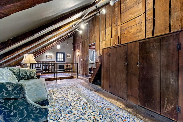 unfurnished room with hardwood / wood-style flooring, lofted ceiling with beams, and wooden walls