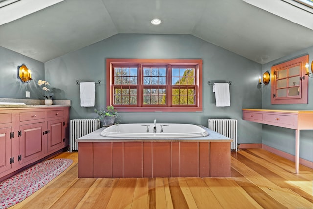 bathroom with hardwood / wood-style floors, lofted ceiling with skylight, and radiator