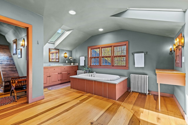 bathroom with vanity, wood-type flooring, radiator heating unit, and lofted ceiling with skylight