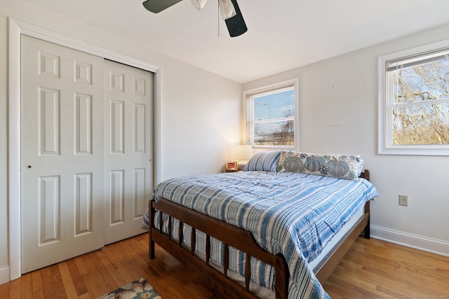 bedroom with hardwood / wood-style floors, ceiling fan, a closet, and multiple windows