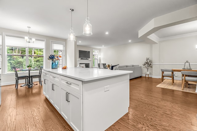 kitchen with hardwood / wood-style flooring, plenty of natural light, white cabinetry, and hanging light fixtures