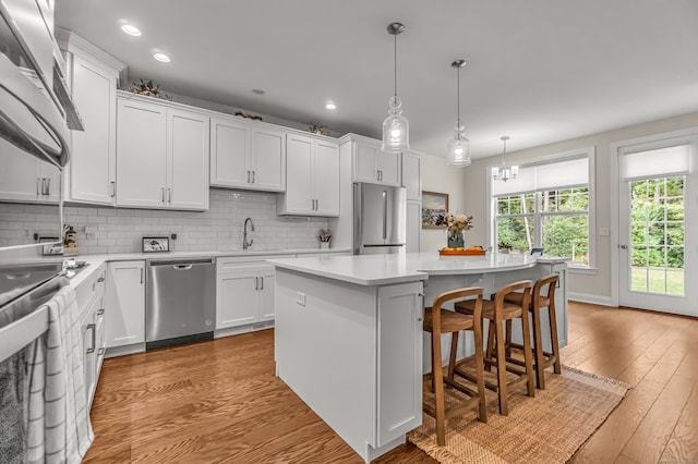 kitchen with light hardwood / wood-style floors, a center island, white cabinetry, and appliances with stainless steel finishes