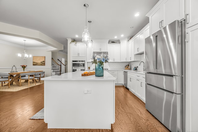 kitchen with high quality fridge, a center island, decorative light fixtures, and light wood-type flooring