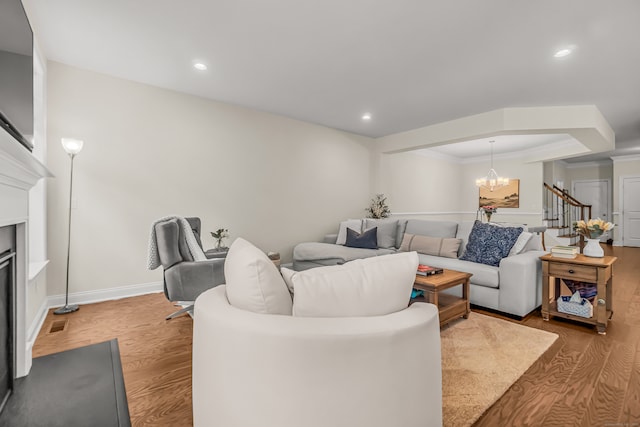 living room featuring ornamental molding, light hardwood / wood-style flooring, and a notable chandelier