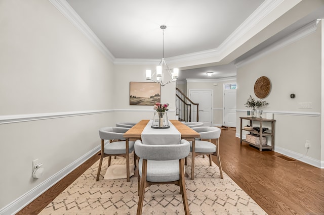 dining area featuring crown molding, hardwood / wood-style floors, and a chandelier