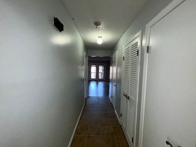 corridor with dark tile patterned flooring and french doors