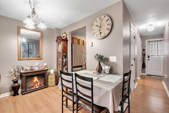 dining room featuring light hardwood / wood-style floors, a chandelier, and a textured ceiling