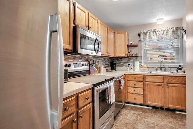 kitchen with appliances with stainless steel finishes, backsplash, sink, and a textured ceiling