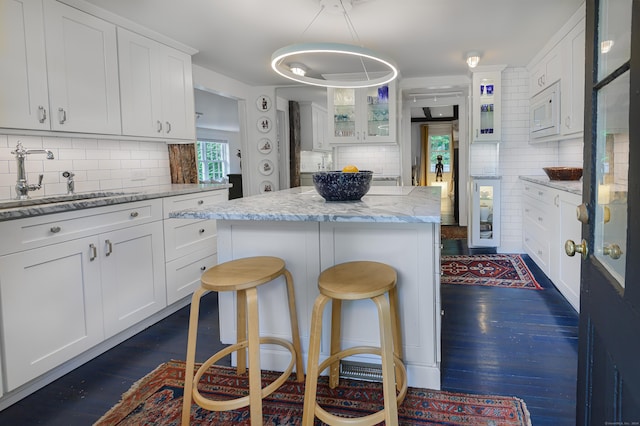 279 Black Rock Tpke, Redding, CT 06896 - kitchen featuring backsplash, a center island, white cabinetry, white microwave, and dark wood-type flooring