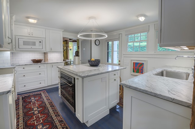 279 Black Rock Tpke, Redding, CT 06896 - kitchen with white appliances, a kitchen island, white cabinetry, tasteful backsplash, and dark wood-type flooring