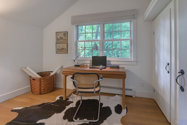 office space featuring a baseboard heating unit, lofted ceiling, and light hardwood / wood-style flooring