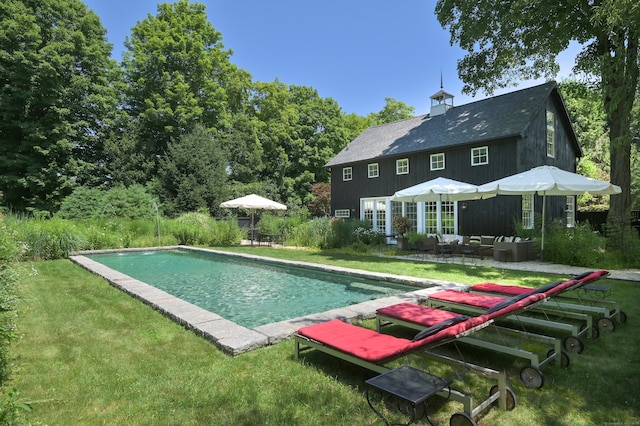 view of pool with outdoor lounge area, a patio, and a lawn