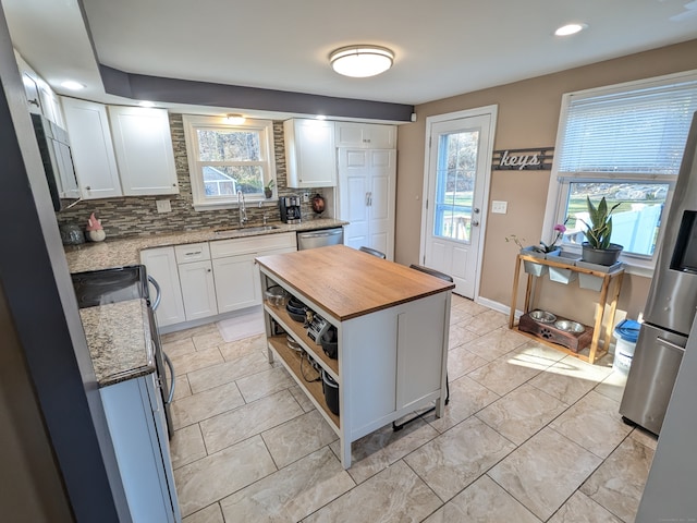 kitchen with a center island, white cabinets, sink, tasteful backsplash, and butcher block counters