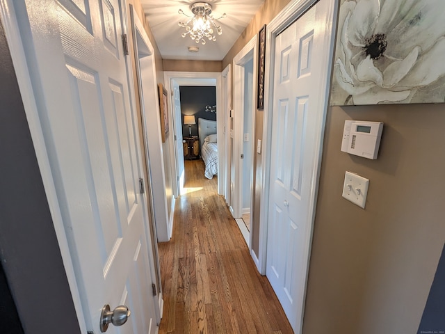 hall with hardwood / wood-style floors and an inviting chandelier