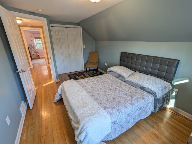 bedroom featuring hardwood / wood-style floors, a closet, and lofted ceiling