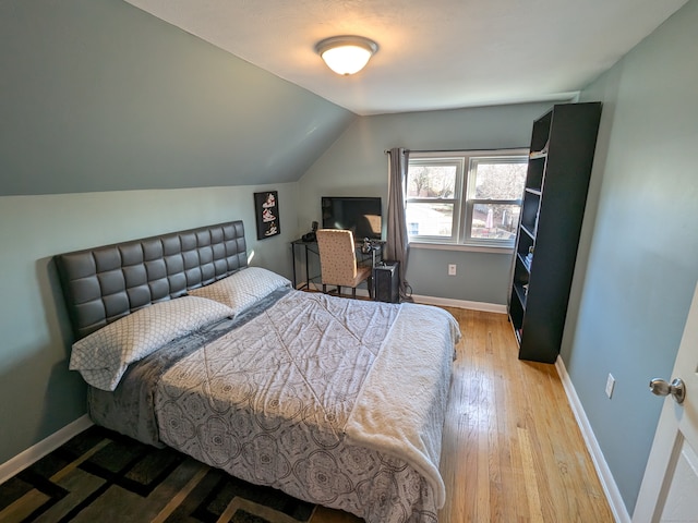 bedroom featuring light hardwood / wood-style floors and lofted ceiling