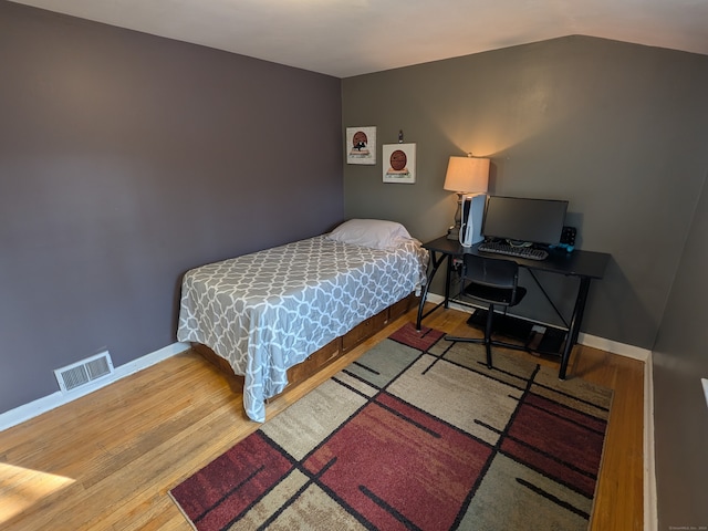 bedroom with wood-type flooring and vaulted ceiling