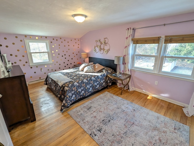 bedroom with a baseboard radiator, vaulted ceiling, and light wood-type flooring