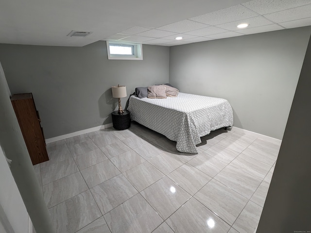 bedroom with a drop ceiling and light tile patterned floors