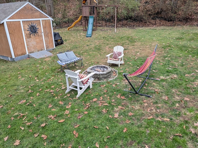 view of yard with a fire pit, a shed, and a playground