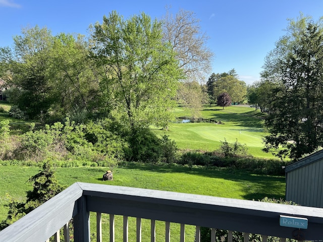 view of grassy yard with view of golf course, a water view, and view of scattered trees
