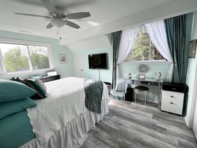 bedroom featuring wood finished floors, a textured ceiling, and a ceiling fan